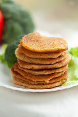 Stack of savory pancakes on a plate with fresh vegetables.