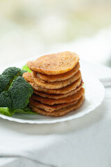 A stack of savory pancakes served with a side of broccoli.  A healthy and delicious meal.