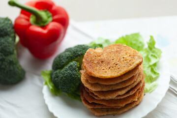 Stack of savory pancakes served with broccoli and bell pepper. A healthy and delicious meal.