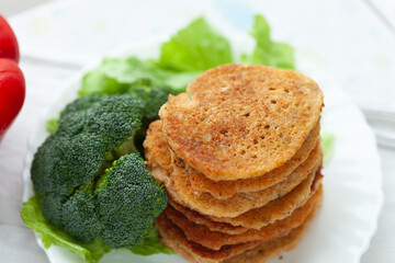 Stack of savory pancakes served with broccoli and lettuce. A healthy and delicious meal.