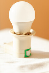 LED light bulb on a simple off-white base with a green switch. The bulb is bright white and sits on...