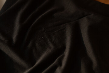 Close-up of dark fabric texture. Soft, draped material with subtle folds and shadows.