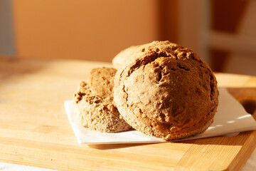 Freshly baked loaves of artisan bread, golden brown and crusty, sit on a wooden board bathed in sunlight.