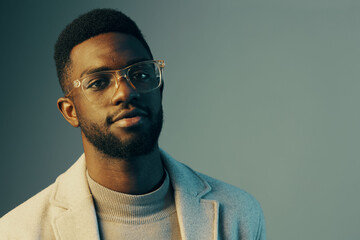 Obraz premium Stylish young African man with glasses posing confidently in a modern setting, showcasing contemporary fashion and vibrant color tones