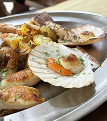Grilled seafood platter with scallops, shrimp, and potatoes on a silver tray