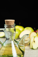 Apple cider vinegar in a glass vinegar bowl among apples