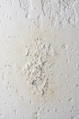 close-up section of plaster finished wall surface with damage caused by moisture, peeling or flaking off with cracks, chips and water penetrated and stained 