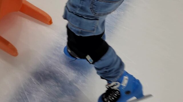 Close-up of the skates of a young boy learning to skate on the ice