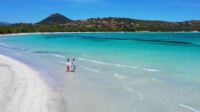 mature couple is walking on the beautiful sandy beach of Santa Giulia, Corsica island
