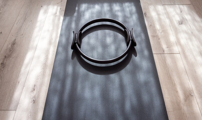 A pilates resistance ring on a yoga mat on a wood floor with interesting shadows