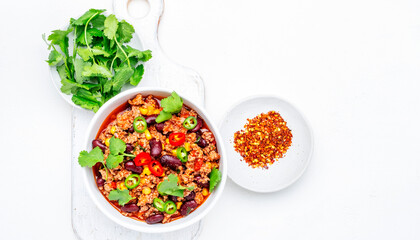 Chili con carne with minced beef, beans, paprika, corn, cilantro, jalapeno pepper in tomato sauce, white background, top view