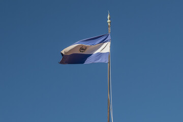 Isolated El Salvador flag waving against blue sky in San Salvador historical center. Independence,...