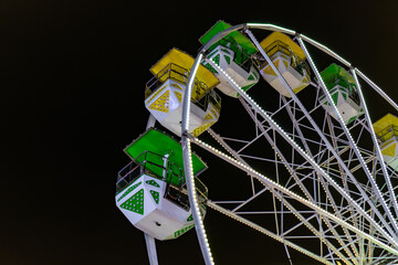 A large Ferris wheel with green and yellow seats