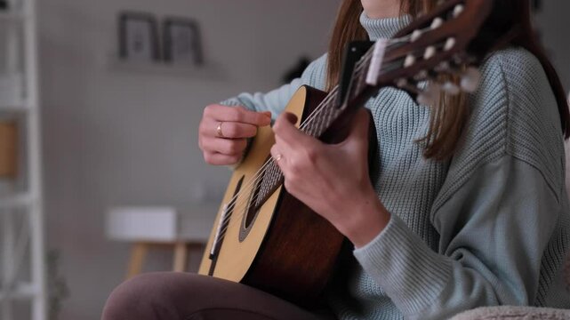 A person playing guitar in a comfortable living room, showcasing various strumming patterns. The warm atmosphere invites relaxation while enjoying the music. High quality 4k footage