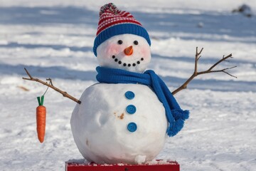 Obraz premium A cheerful snowman with a carrot nose, blue scarf, and hat, standing in snowy landscape.
