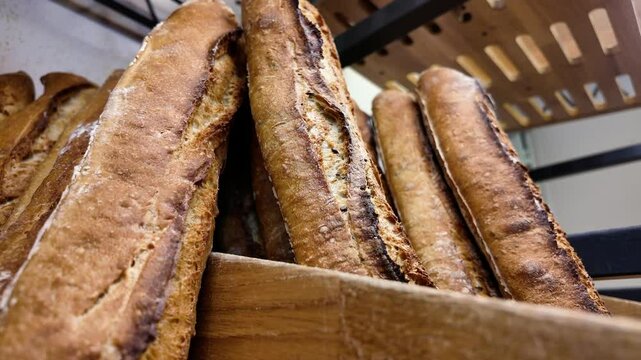 Pr&eacute;sentation en boulangerie de la Traditionnelle Baguette de pain Fran&ccedil;aise avant la vente. Le pr&eacute;sentoir est en bois et m&eacute;tal noir la cam&eacute;ra effectue un mouvement de gauche &agrave; droite en diagonale d