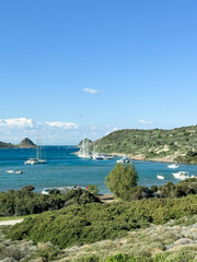 Fototapeta premium Sailboats anchored in a tranquil bay surrounded by lush hills and clear blue skies