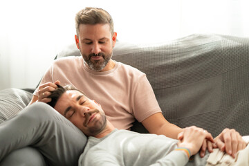 Fototapeta premium two lgtbi couple boys relaxing on the sofa at home while one of them touches their hair