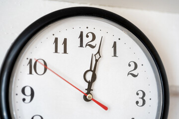Simple clock close-up, showing minutes past noon just past 12 AM or twelve PM time concept. Punctuality, running late, being late abstract concept, deadlines and schedule management, past midnight