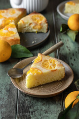 Upside down orange tangerine cake or pie slice on a plate on green wooden background. Fruit citrus pastry. Homemade winter baking