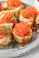 Pancake day, maslenitsa. Crepes, pancakes rolled with red caviar on white plate, close up