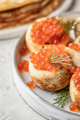 Pancake day, maslenitsa. Crepes, pancakes rolled with red caviar on white plate, close up