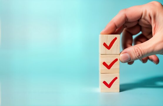 Hand places wooden cube with red checkmark on checklist. Simple task management concept. Person completes item on to-do list. Organization, productivity theme. Image shows simple checklist. Light