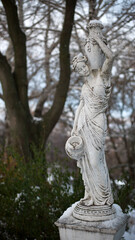 sculpture of a girl in the winter park. An old statue in a park of a sensual semi-nude Greek or Italian Renaissance woman with a vase. sunny day, spring garden. 