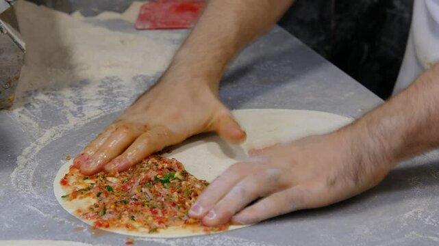 Male hands making lahmacun 