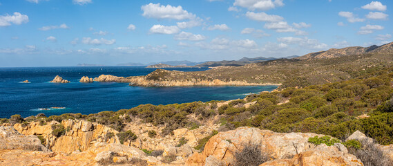 Landscape of the south-west coast of Sardinia with cliffs, blue sea, fjords and white clouds