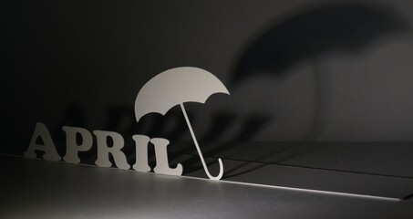 Angled letters spelling April against silhouette shadows