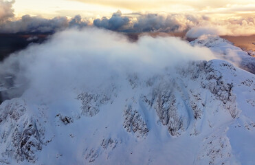 A Majestic SnowCapped Mountain Surrounded by Soft Clouds at Sunset, Truly Stunning