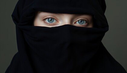 Naklejka premium Mysterious Woman with Blue Eyes Partially Hidden by a Dark Veil in Studio Portrait Photography