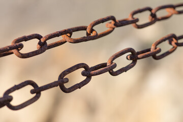 Fototapeta premium Rusty chain with oval links stretched between supports. Connection of engineering structures.