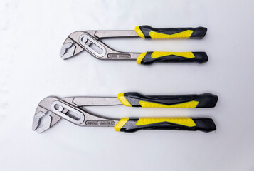 Two chrome vanadium steel water pump pliers with yellow and black handles resting on white background