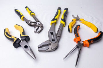 Different pliers and wrenches laying on white background