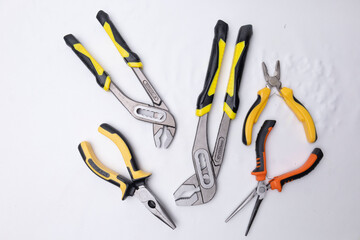 Different pliers and groove joint pliers lying on white background