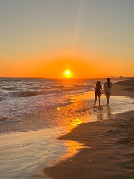 Two people walking on a beach at sunset in vale do lobo portugal