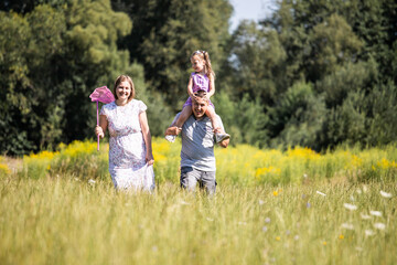 Fototapeta premium Parent and child. Happy family. Mom, dad and child relaxing in nature. Family in the park. Family having fun. Daughter