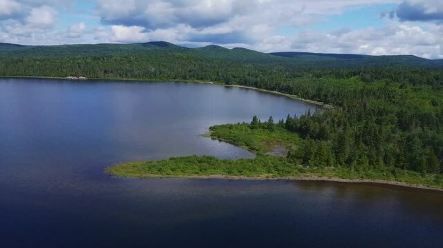 Panoramic Drone View of a Peaceful Forested Bay and Peninsula on Lake Matapedia under a cloudy sky., Quebec, Canada 