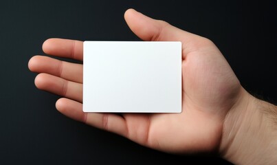 Blank white card held in hand against dark background, showcasing empty space for customization or branding