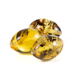 Three yellow and brown amber beads are sitting on a white background