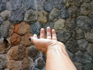 open hand and stone wall in the background
