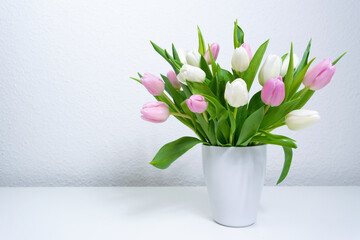Bouquet of fresh natural white and purple tulips in a white vase. Greeting card.