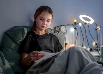 Smart Cute Little Girl Reading A Book In Bed Before Sleep