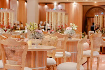 Elegant event space with light wood chairs and floral centerpieces. Perfect for weddings or corporate events.