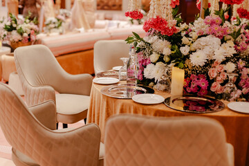 Elegant wedding reception table setting with a beautiful floral centerpiece.  Beige chairs and gold tablecloth create a luxurious atmosphere.