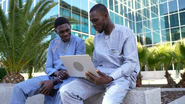 Senegalese businessmen wearing dashiki using laptop outdoors