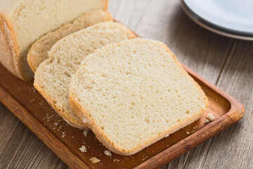 Slices of fresh homemade white bread made by a bread making machine, served on wooden board (Selective Focus, Focus in the middle of the image)