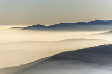 The mountains are covered in fog and the sky is a mix of blue and white
